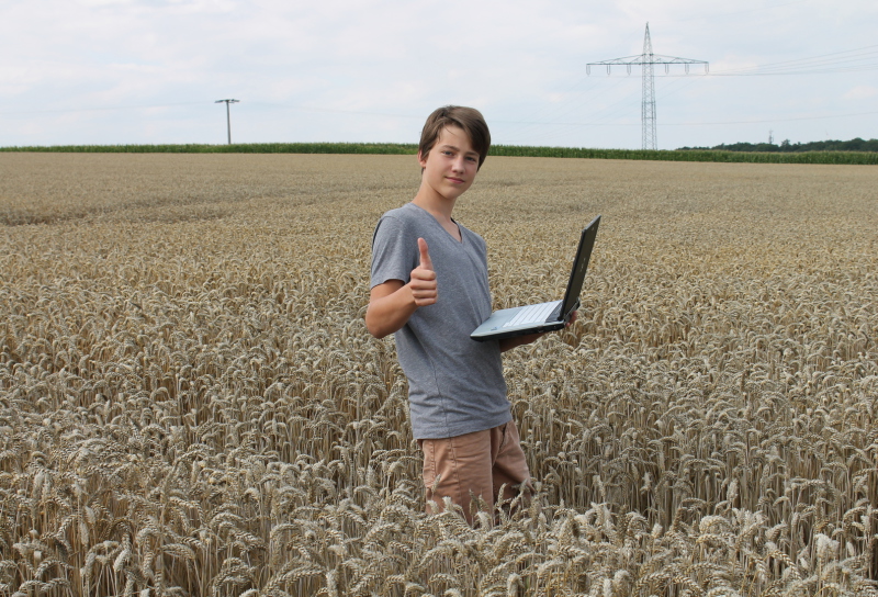 Auszubildender mit Laptop im Getreidefeld